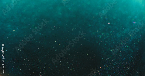 Bokeh light overlay. Blur glitter texture. Shimmering water bubbles. Defocused verdigris green blue orange color particles on dark abstract background. photo
