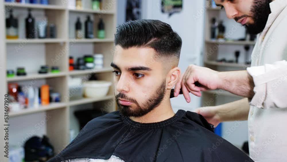 Barber shaves the neck of a client sitting in a chair in a barbershop. Barber shaves the neck of a client sitting in a chair in a barbershop.