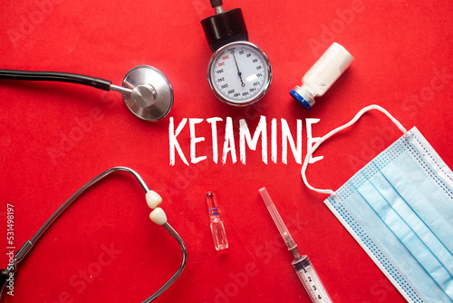 Inscription ketamine. Top view of the table with stethoscope, medical mask and stethoscope with syringe. Health care concept