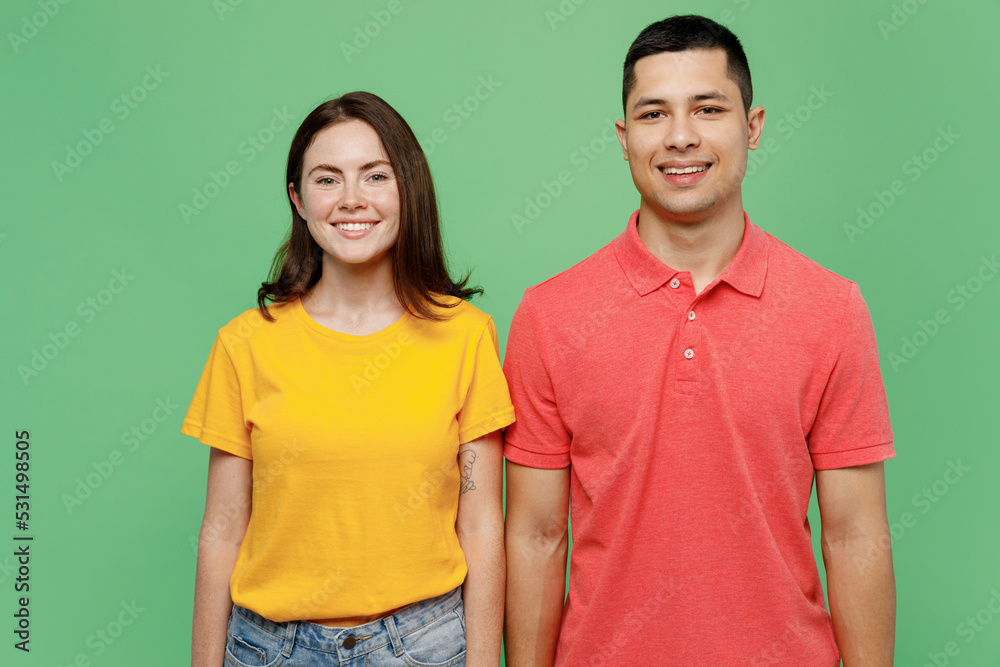 Young smiling happy fun cool cheerful joyful couple two friends family man woman 20s wear basic t-shirts looking camera together isolated on pastel plain light green color background studio portrait. Young smiling happy fun cool cheerful joyful couple two friends family man woman 20s wear basic t-shirts looking camera together isolated on pastel plain light green color background studio portrait.