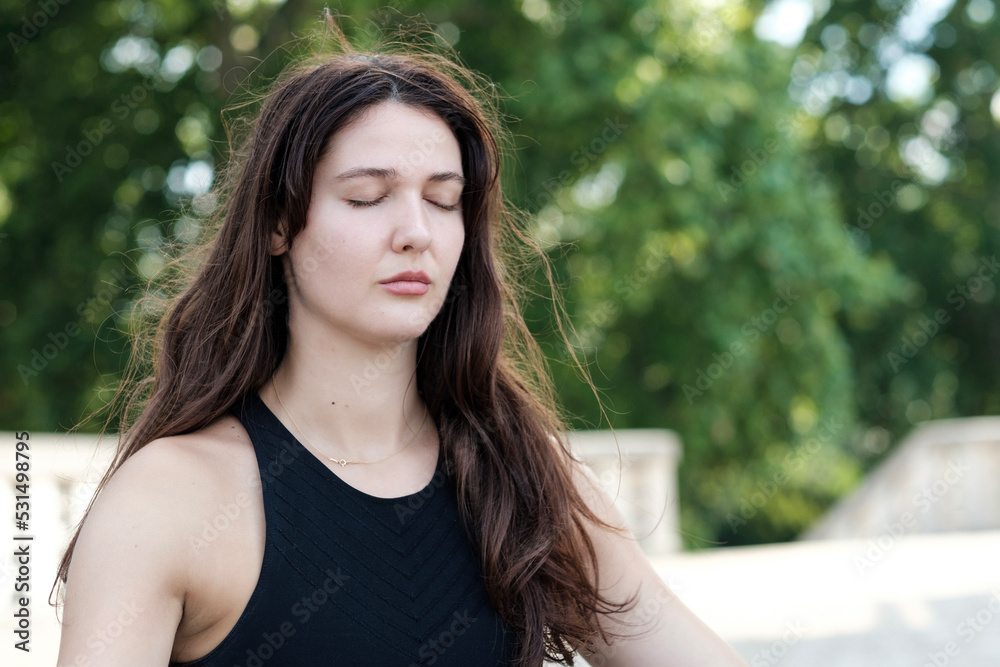 Portrait of spiritual young caucasian woman doing yoga outdoors.