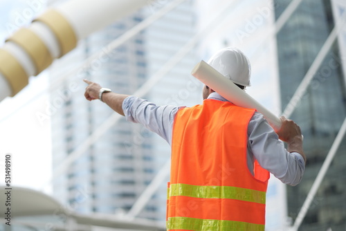 Architect or engineer with blueprints. Cauacsian Engineer checking plan on construction site. modern structure. helmet and blueprints paper. photo