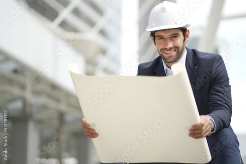Architect or engineer with blueprints. Cauacsian Engineer checking plan on construction site. modern structure.