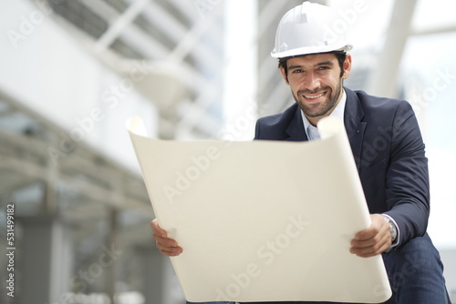 Architect or engineer with blueprints. Cauacsian Engineer checking plan on construction site. modern structure. photo