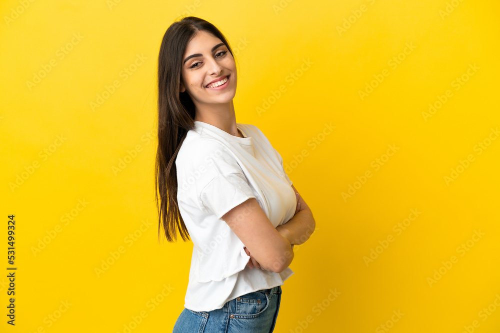 Young caucasian woman isolated on yellow background with arms crossed and looking forward