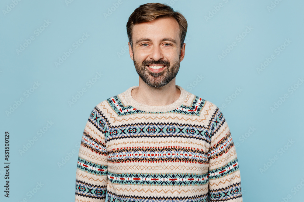 Fototapeta premium Young satisfied positive fun cool smiling happy fun cool cheerful man 30s he wearing sweater look camera isolated on plain pastel light blue cyan background studio portrait. People lifestyle concept.