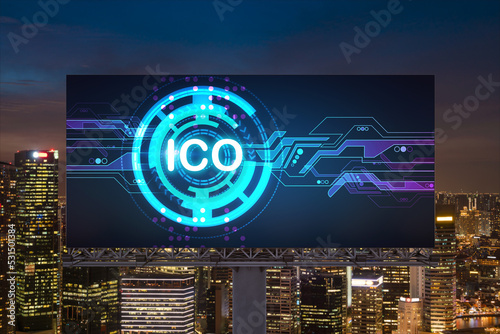 ICO hologram icon on billboard over panorama city view of Singapore at night time. The hub of blockchain projects in Southeast Asia. The concept of initial coin offering, decentralized finance
