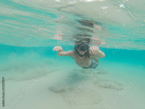 Bearded and long haired man snorkeling at Lion's Beach (Praia do Leão), Fernando de Noronha archipelago, Brazil