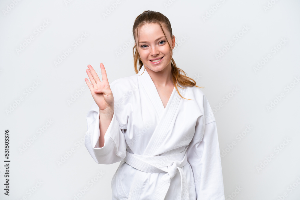 Young caucasian girl doing karate isolated on white background happy and counting four with fingers Young caucasian girl doing karate isolated on white background happy and counting four with fingers