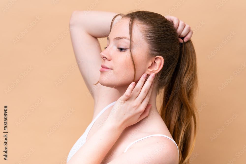 Young caucasian girl isolated on beige background touching her hair. Close up portrait Young caucasian girl isolated on beige background touching her hair. Close up portrait