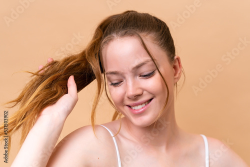 Young caucasian girl isolated on beige background with happy expression. Close up portrait