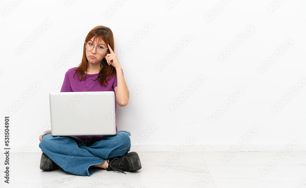 redhead girl with a laptop sitting on the floor thinking an idea redhead girl with a laptop sitting on the floor thinking an idea