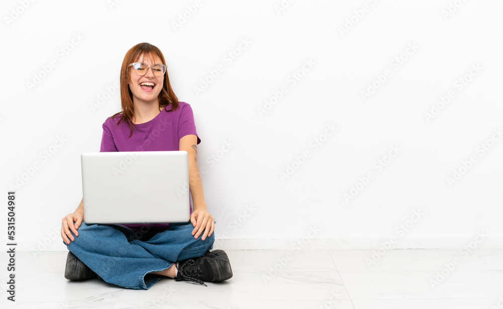 redhead girl with a laptop sitting on the floor laughing redhead girl with a laptop sitting on the floor laughing