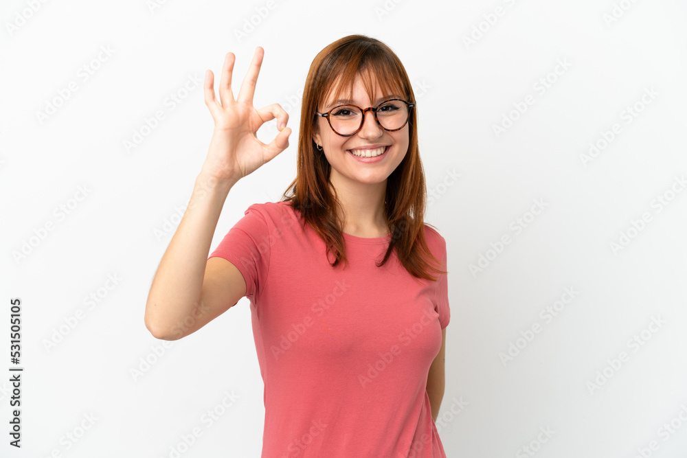 Redhead girl isolated on white background showing ok sign with fingers Redhead girl isolated on white background showing ok sign with fingers
