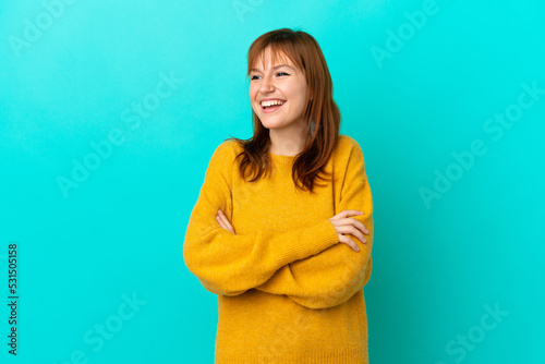 Redhead girl isolated on blue background happy and smiling