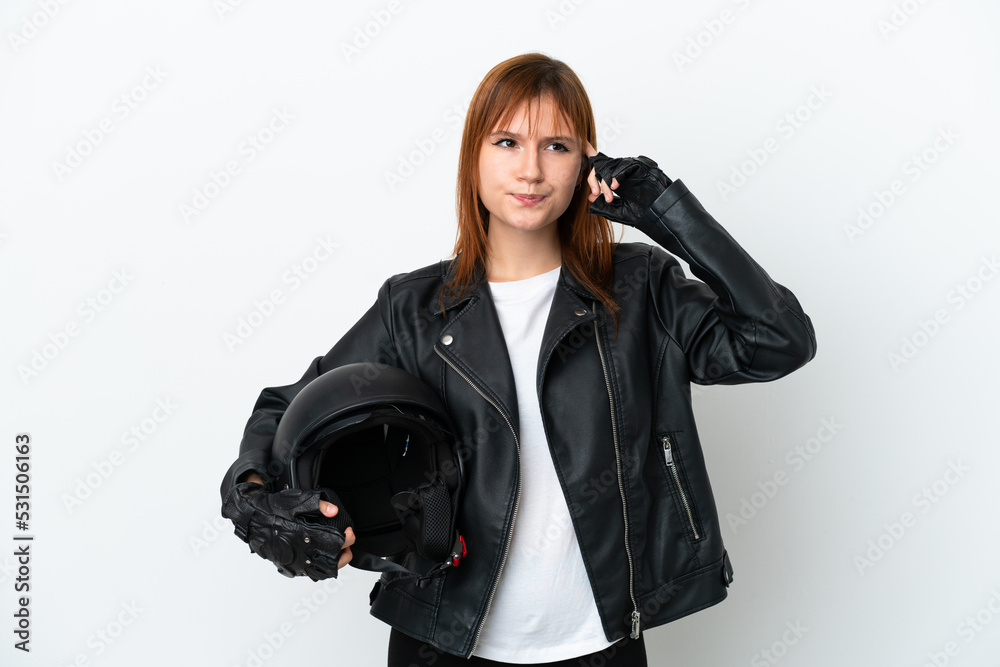 Redhead girl with a motorcycle helmet isolated on white background having doubts and thinking Redhead girl with a motorcycle helmet isolated on white background having doubts and thinking