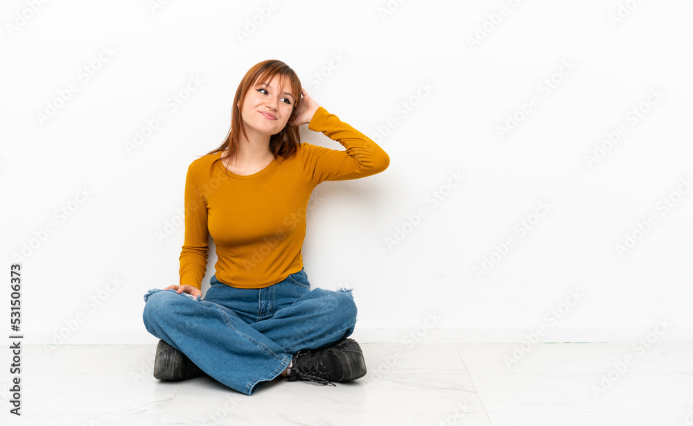 Redhead girl sitting on the floor isolated on white background thinking an idea Redhead girl sitting on the floor isolated on white background thinking an idea