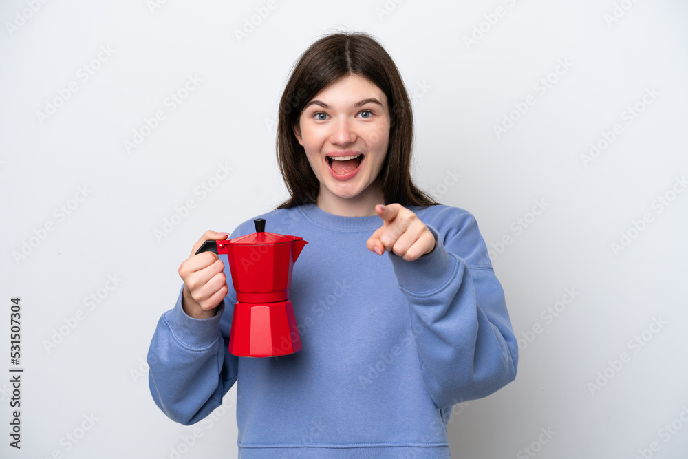 Young Russian woman holding coffee pot isolated on white background surprised and pointing front Young Russian woman holding coffee pot isolated on white background surprised and pointing front