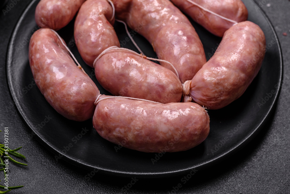 Raw barbecue sausages on a wooden cutting board with spices and herbs Raw barbecue sausages on a wooden cutting board with spices and herbs