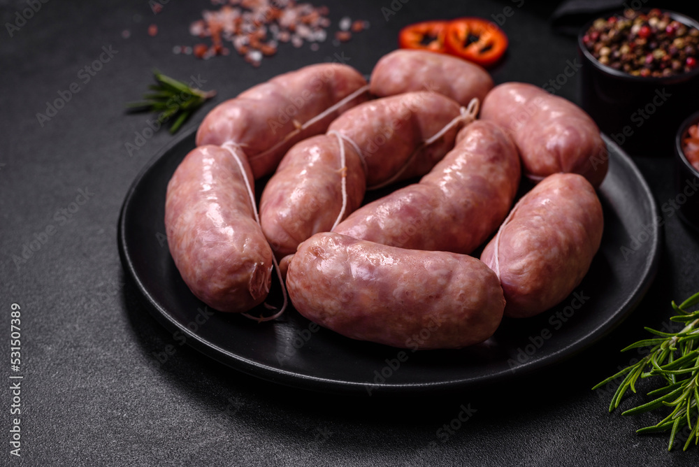 Raw barbecue sausages on a wooden cutting board with spices and herbs Raw barbecue sausages on a wooden cutting board with spices and herbs