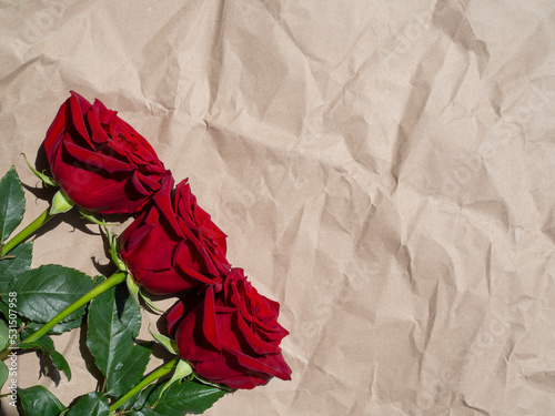 Red roses on vintage craft paper. Greeting card for holiday text. Top view, flat lay