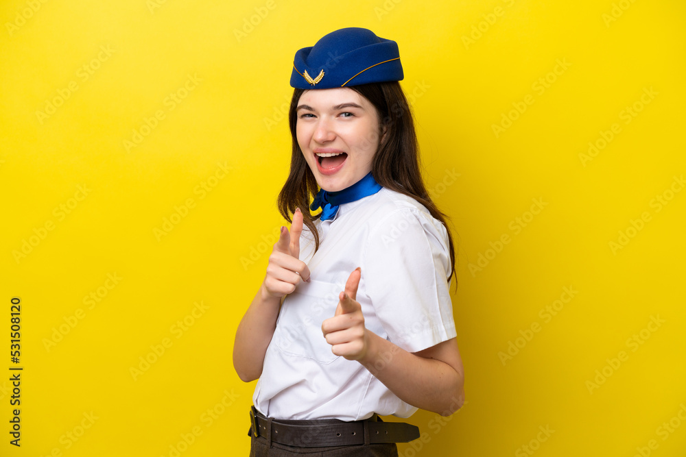 Airplane stewardess Russian woman isolated on yellow background pointing to the front and smiling Airplane stewardess Russian woman isolated on yellow background pointing to the front and smiling