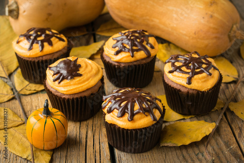 Pumpkin muffins with chocolate decor and cream of cottage cheese on Halloween. Style vintage. Selective focus