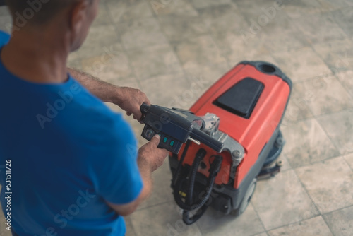 A cleaning worker turns on the machine to wash the hard floor