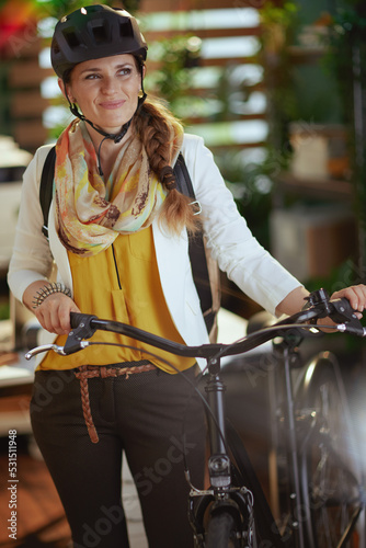 smiling stylish business woman in bike helmet in eco office
