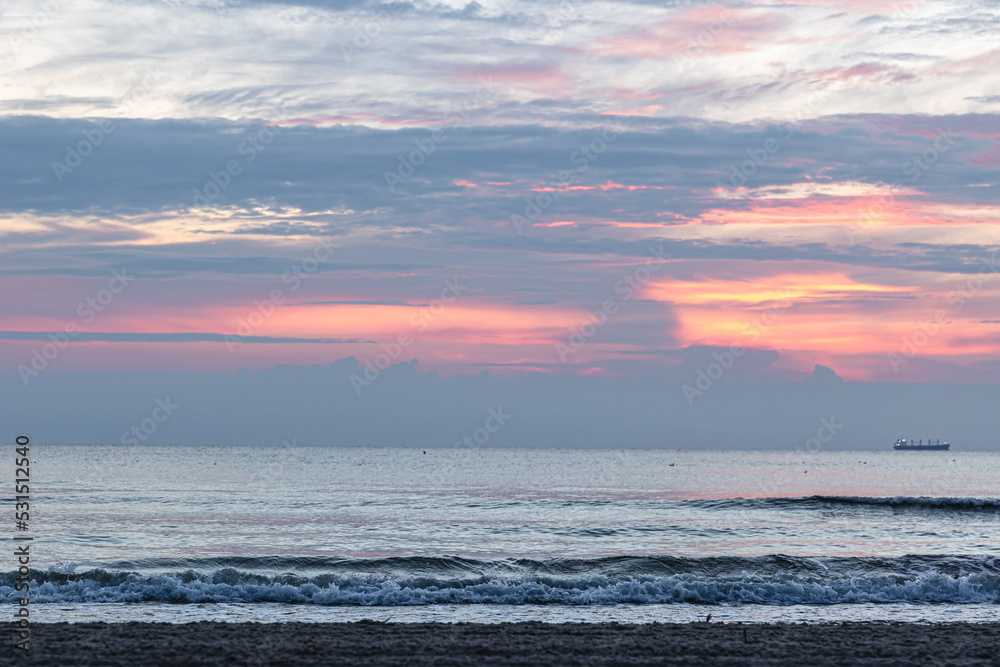 Fototapeta premium Texture sea waves at sunset with pink clouds.