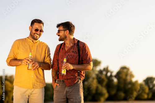Two handsome male friends walking along the beach and hanging out talking Summer time stock photo