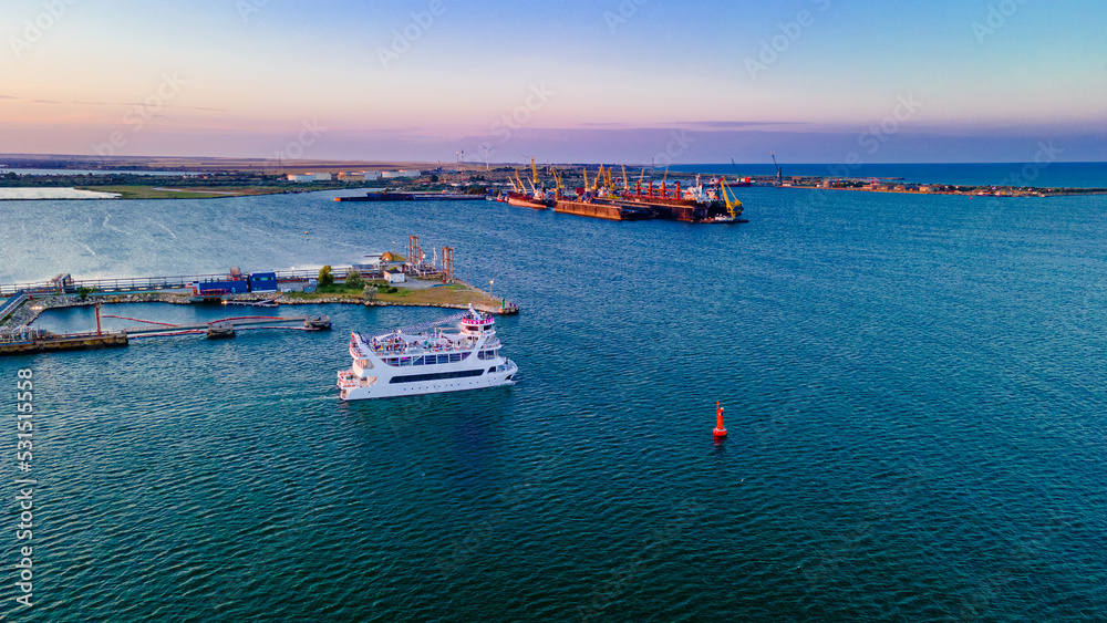 Aerial view of a harbor with ships sailing and docked. Photography was taken from a drone at a higher altitude in summer season at sunset.