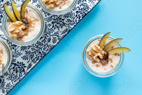 Dessert mit Pflaume, Walnuss, Frischkäse, Joghurt. Quark, Haferflocken, Marmelade und Zimt auf einem Tisch angerichtet photo