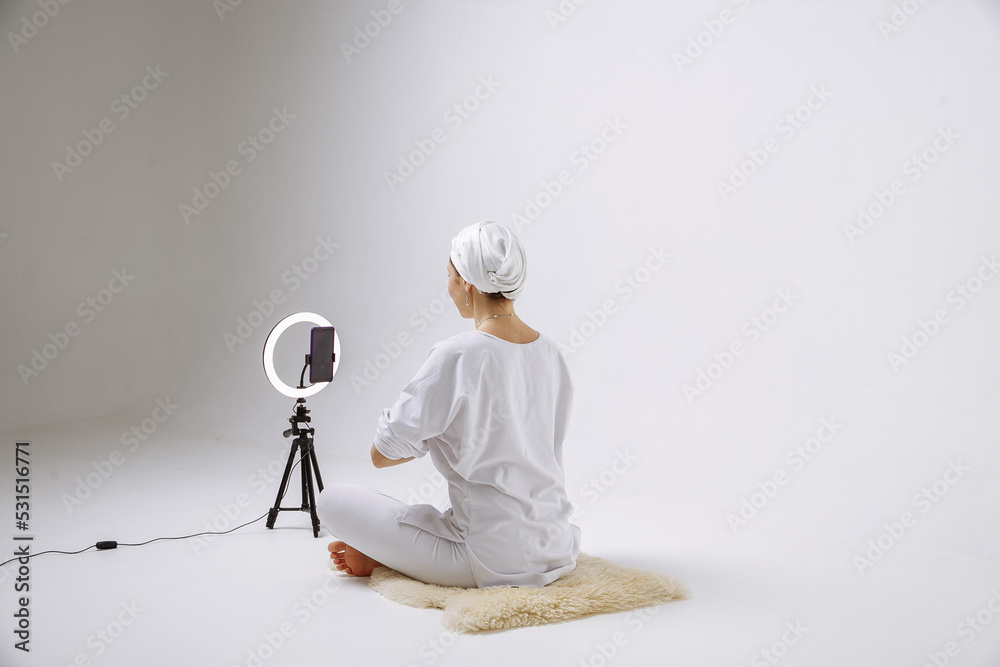 A girl in white clothes is doing yoga, live on the background of the phone