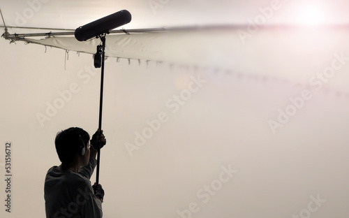 Boom Microphone for sound recording in film industry. Sound boom operator recording sound by microphone fisher for movie set in studio. Boom mic holds up high by video or film production crew team man photo