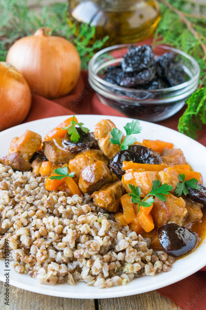 Pork stew with carrots and prunes. Pork with buckwheat. Wooden background. Selective focus Pork stew with carrots and prunes. Pork with buckwheat. Wooden background. Selective focus