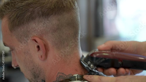 barber doing a close buzz cut to young mans neck and hair line photo