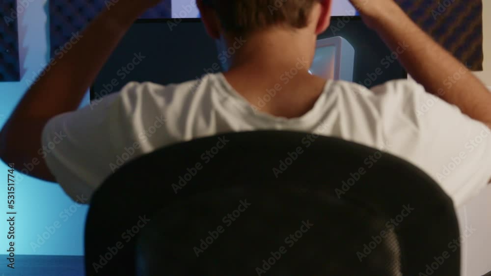 Boy walking to his gaming setup to pick up his PS5 controller and headset then starts gaming on his PlayStation 5 in an RGB LED room at night, Close