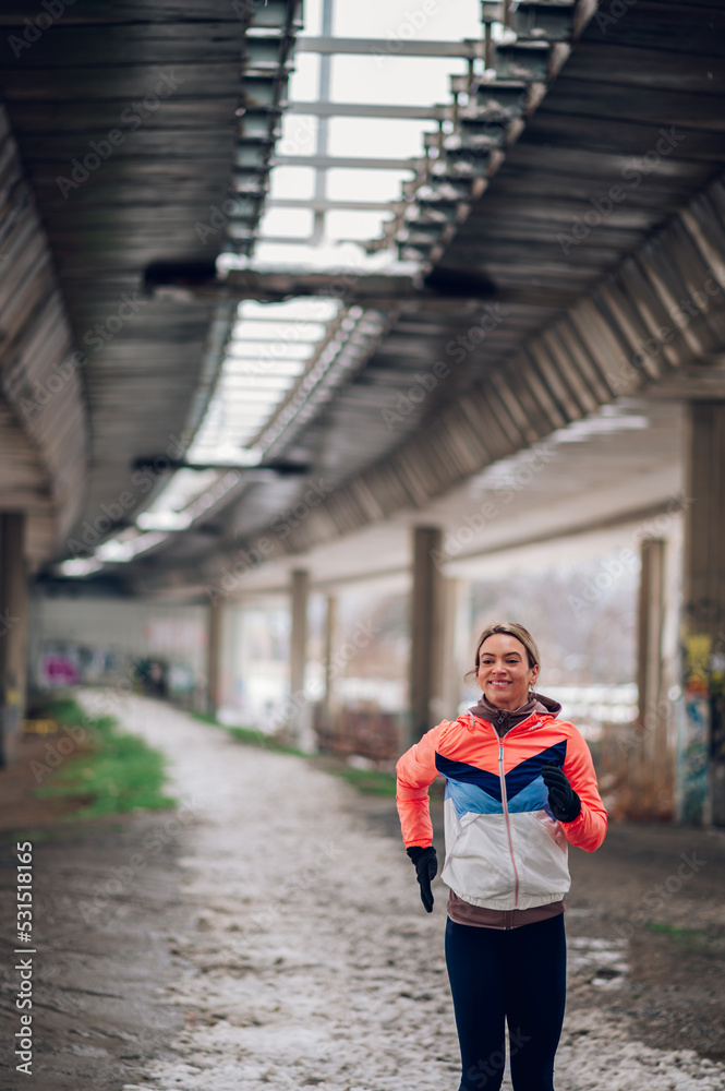 Woman running under the bridge on a cold winter day.