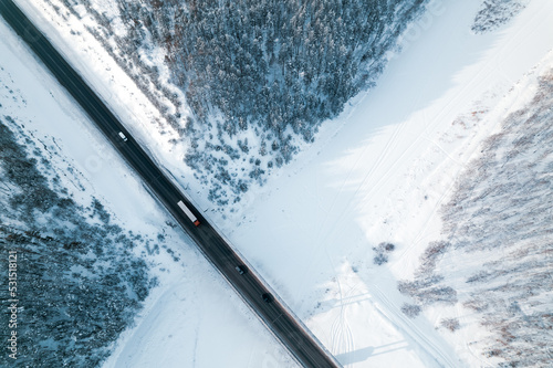 aerial view, cars drive along the road. winter forest and bridge