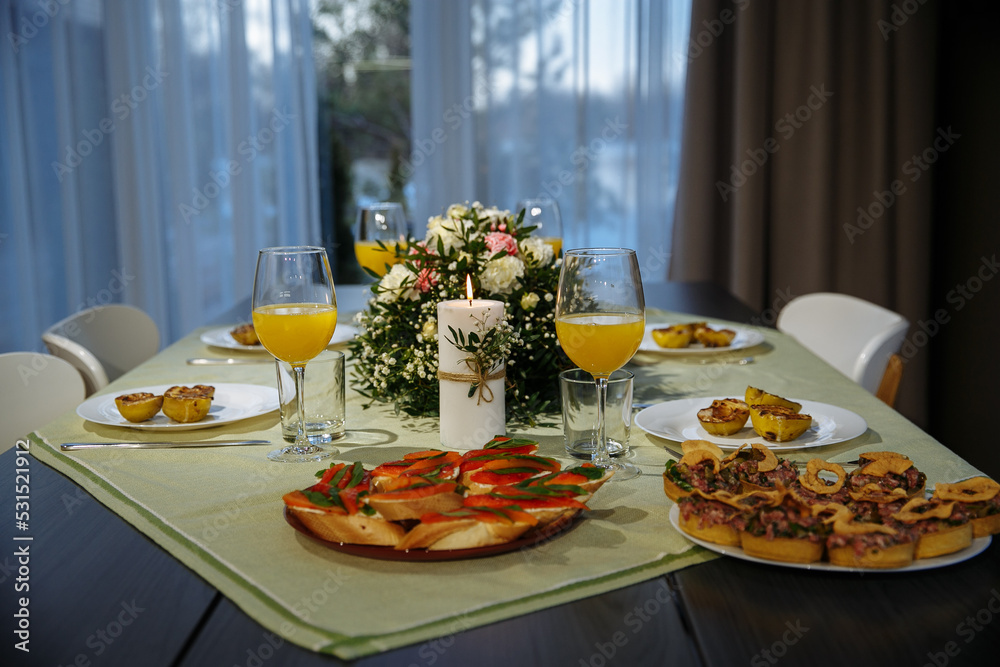 Glasses with yellow juice on the table, with flowers in the room