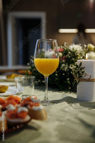 Glasses with yellow juice on the table  with flowers in the room