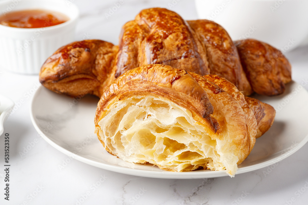 Fresh sweet croissants with apricot jam for breakfast. Continental breakfast on a white table Fresh sweet croissants with apricot jam for breakfast. Continental breakfast on a white table