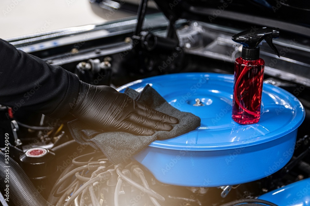 Car mechanic or car wash worker will clean the car engine with a cloth. Car care
