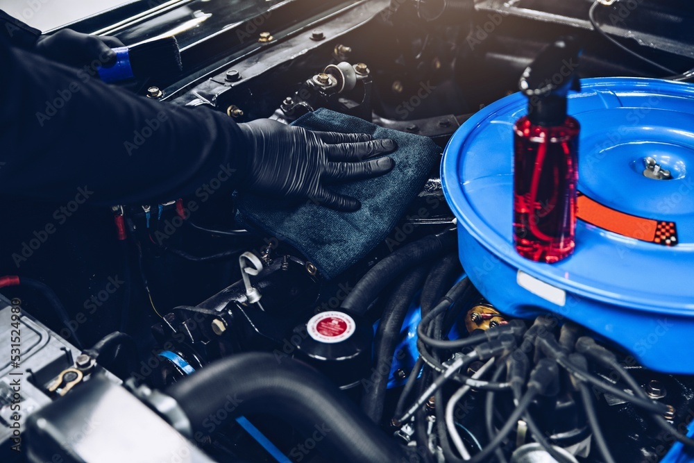 Car mechanic or car wash worker will clean the car engine with a cloth. Car care