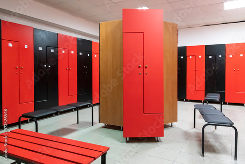 Foto Empty changing room in fitness gym with group of red and black wooden lockers standing in a row by wall