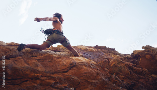 Mountain, sport and climbing with a sports man running along a rocky surface for health, fitness and exercise. Workout, training and cardio with a young male climber athlete in the mountains
