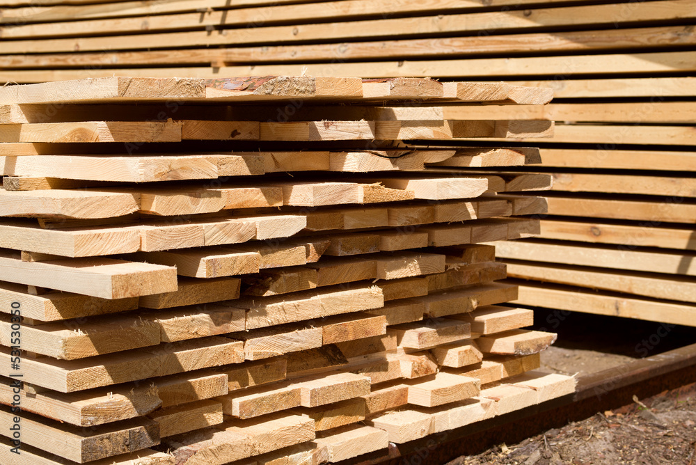 Stack of fresh pine boards in a sawmill warehouse. Harvesting, sale of lumber for construction Stack of fresh pine boards in a sawmill warehouse. Harvesting, sale of lumber for construction
