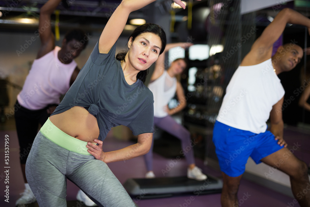 Woman with others doing step aerobics in a fitness club