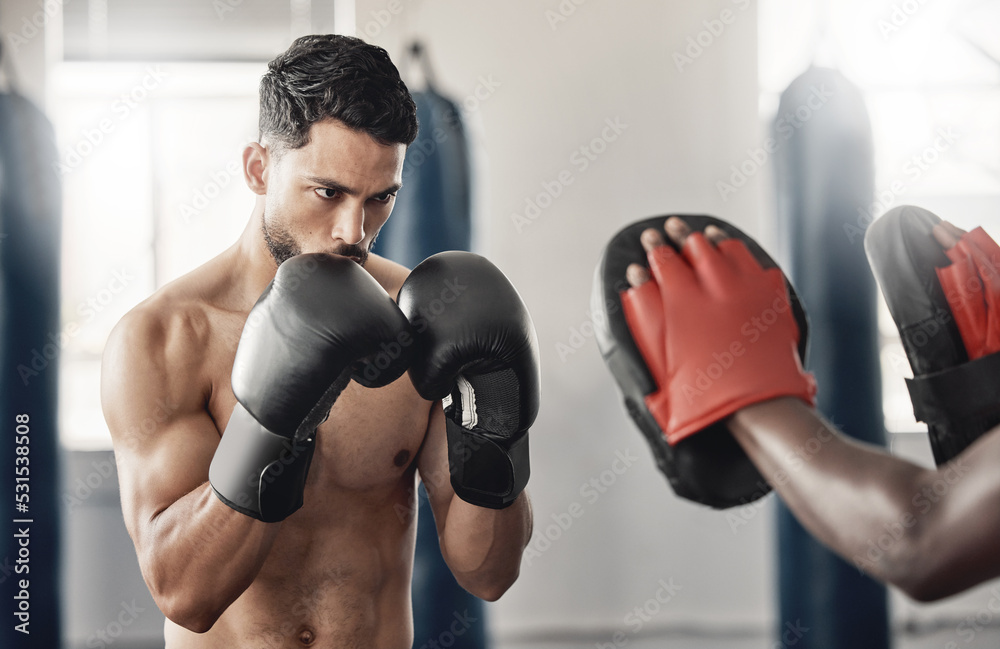 Boxing gym, fighting pad and man training with athlete coach for a fitness cardio exercise session. Strength, focus and fighter workout for punch technique with professional sports equipment.
